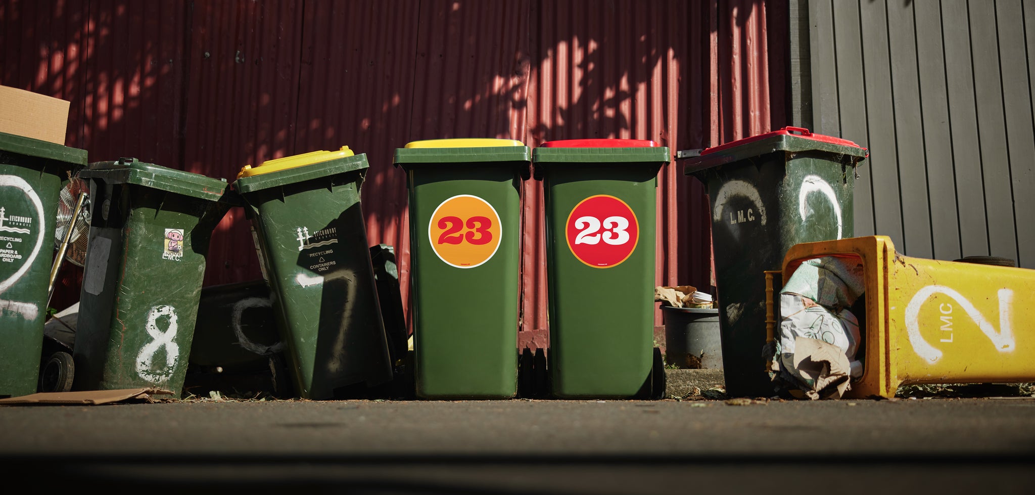 Pair of Custom Suburbin bin stickers looking beautiful amongst other trashy bins in a laneway. 
